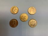 quatre types différents de pièces d'or sur une surface blanche