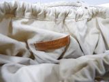 a close up of a white pants with a leather label