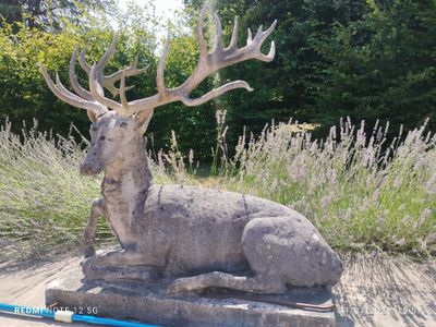 une statue représentant un cerf assis dans l'herbe