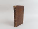 un petit livre marron posé sur une surface blanche