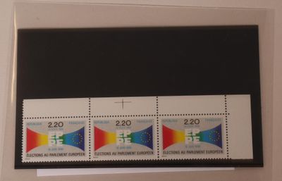 Trois timbres de couleurs différentes sont accrochés sur un mur blanc.