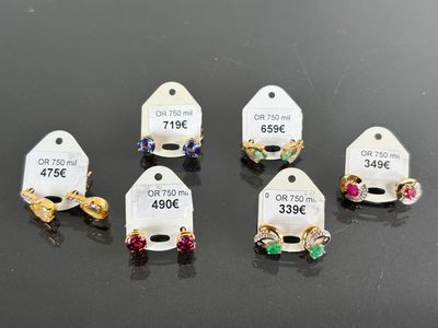 six pairs of earrings with price tags on them sitting on a table
