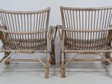 pair of bamboo chairs with woven seats against a white wall