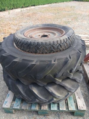 un gros pneu posé sur une palette, à côté d'un tas de pneus