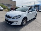La voiture blanche est garée sur un parking près d'un immeuble.