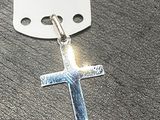 une croix en argent à laquelle est attachée une étiquette