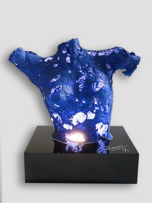 a blue sculpture on a black stand with a light on it