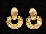 paire de boucles d'oreilles dorées avec des anneaux circulaires, présentées sur du velours noir