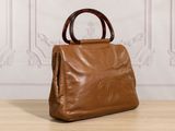 a brown handbag sitting on top of a wooden table