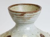 a white and brown vase with holes in it