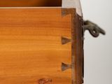 close up of a wooden drawer with a metal handle on a white wall