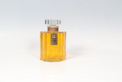 un vieux flacon de parfum posé sur une surface blanche