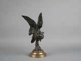 statue en bronze représentant un oiseau sur un socle, sur fond gris