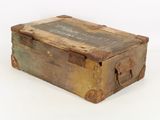 an old wooden box with a metal lid on a white surface