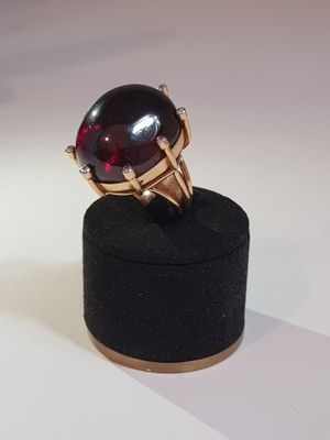 a black ring with a red stone on top of a black box