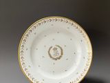 a white and gold plate with a gold decoration on it