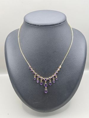a purple and gold necklace on a mannequin display