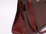 brown leather handbag on a white background with a gold clasp