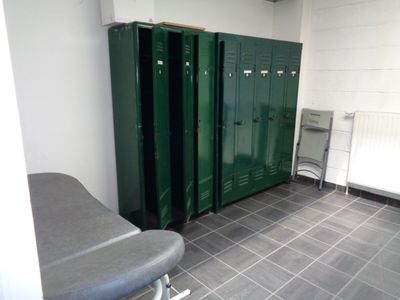 plusieurs casiers verts dans une pièce équipée d'un banc et d'un radiateur