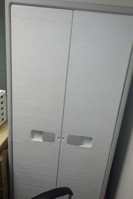 une armoire blanche et une chaise noire dans une pièce