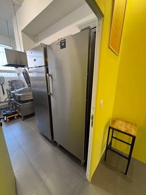 a stainless steel refrigerator in a kitchen with a yellow wall