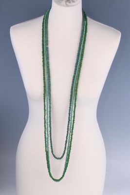 un mannequin blanc orné de perles vertes et d'un collier