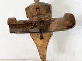 wooden sculpture of a man holding a wooden cross on a stand