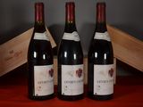three bottles of red wine sit on a table next to a wooden box