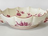 a white bowl with pink flowers on it on a white surface