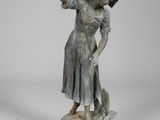 bronze statue of a woman with a broom and a hat