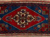 un vieux tapis aux motifs rouges et bleus posé sur un parquet
