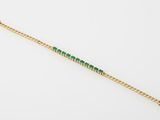 a gold bracelet with emerald stones on a white background