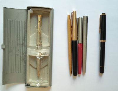 une boîte contenant des stylos, un stylo et un crayon posée sur une table
