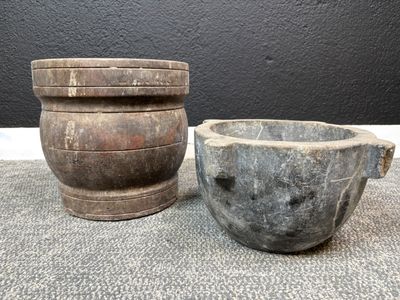 une paire de mortiers anciens en bois et un bol en pierre posés sur une table