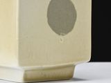 a white vase with a black dot on it