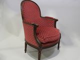 une vieille chaise dont l'assise est recouverte d'un tissu rouge sur fond blanc