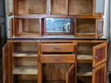 a wooden cabinet with two doors open and a refrigerator in the background