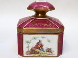 a small pink and gold box with a painting on it