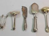 five silver spoons and two silver spoons on a white surface
