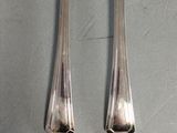 two silver spoons and a fork on a gray surface
