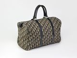 un sac de voyage marron et noir posé sur une surface blanche