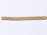 a close up of a gold chain bracelet on a white surface