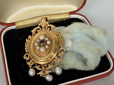 a gold brooch with pearls in it in a case