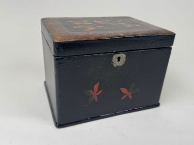 une petite boîte noire sur laquelle sont peintes des fleurs rouges