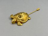 une broche en forme de tortue dorée sur un fond gris