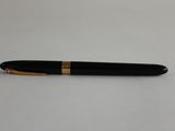 un stylo noir et doré posé sur une table blanche