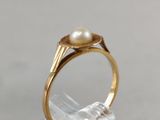 an image of a gold ring with a pearl on top of a clear glass