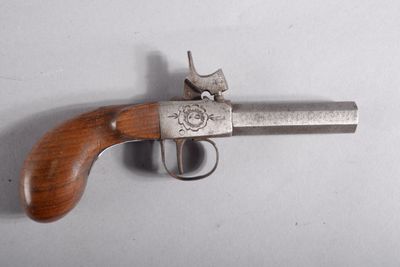 un gros plan d'un pistolet posé sur une surface blanche, avec une crosse en bois