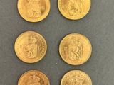 six gold sovereigns of different sizes and shapes on a gray surface