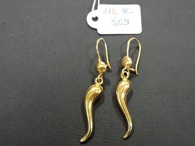 une paire de boucles d'oreilles en or posées sur une surface noire, avec une étiquette de prix